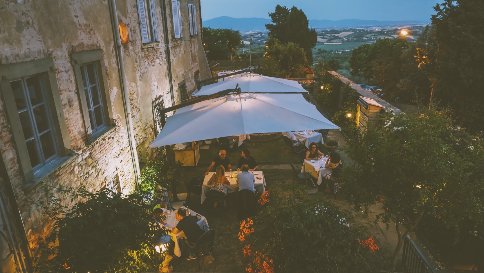 Restaurant patio lit by laterns under white tent.